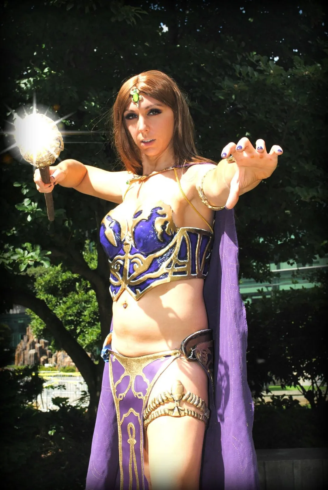 Jerikandra as Antonia Bayle from EverQuest II in a purple and gold armored gown and circlet, holding a glowing scepter outdoors.