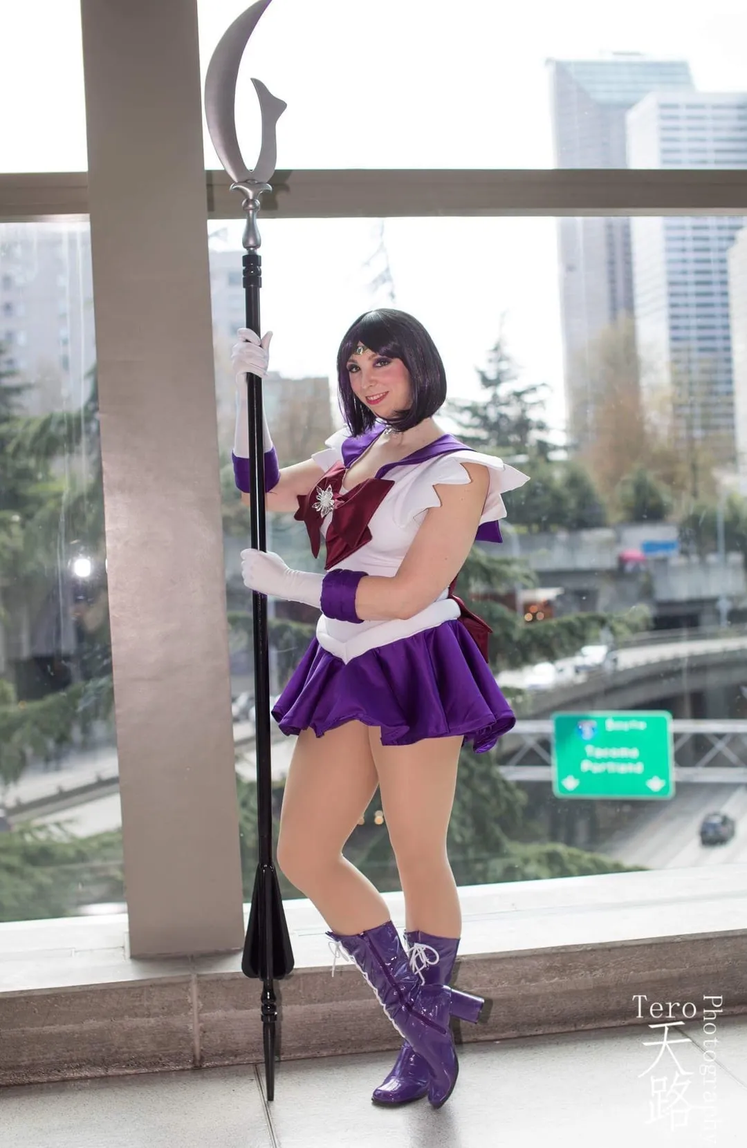 Jerikandra as Sailor Saturn from Sailor Moon in a purple sailor uniform and boots, holding the Silence Glaive above a highway.